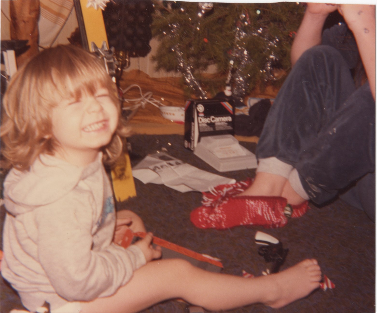 Young child laughing beside a Christmas tree
